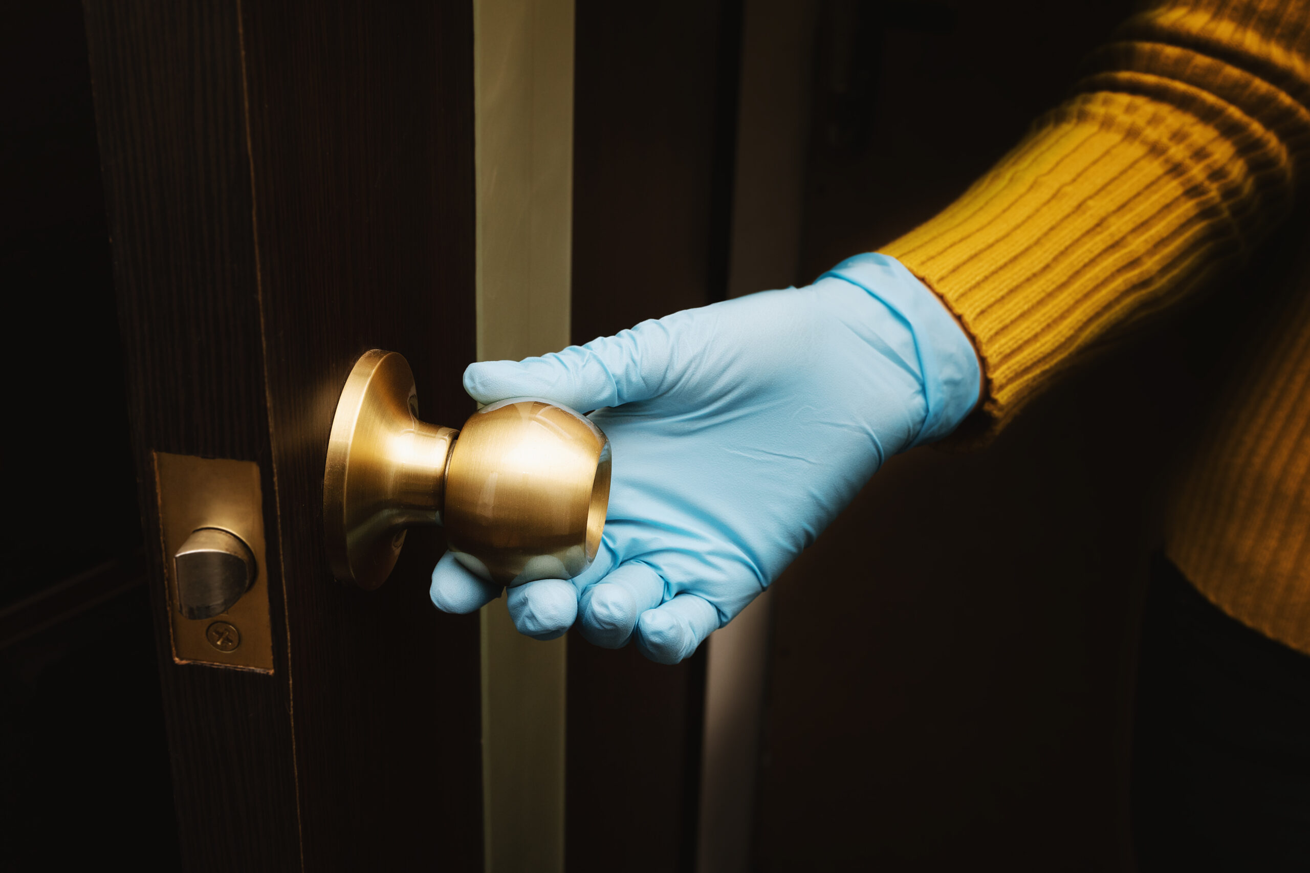 Female hand in protective glove open a door.